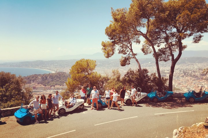Quelques NiceCar garées le long d´une route avec une belle vue sur Nice et la mer au fond
